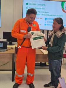 Emerson, profissional da Refap/Petrobras, recebendo do Cacique José Cirilo kit sobre o projeto, desenvolvido com 10 aldeias Guarani no RS